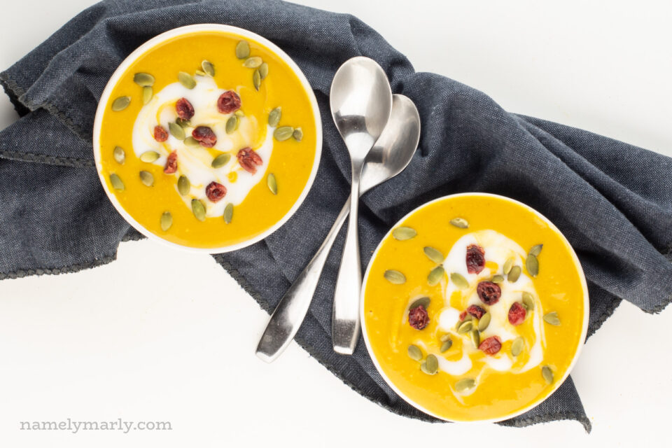 Looking down on two bowls of soup with two spoons between them.
