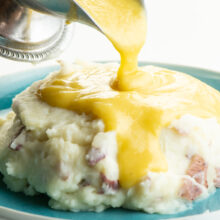 Vegan gravy is poured over a big plate of mashed potatoes.