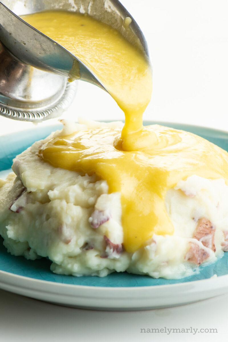Vegan gravy is poured over a big plate of mashed potatoes.