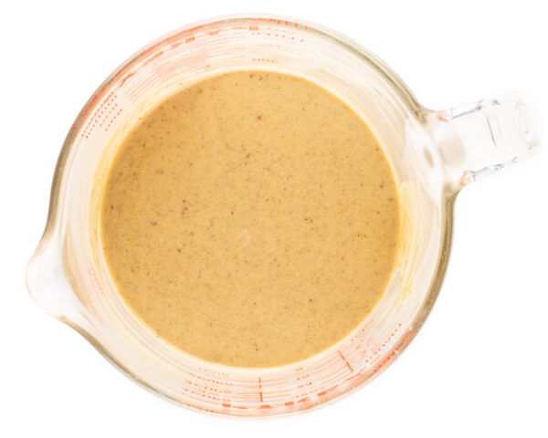 A bowl of the sauce used to make granola in a glass pyrex measuring cup.