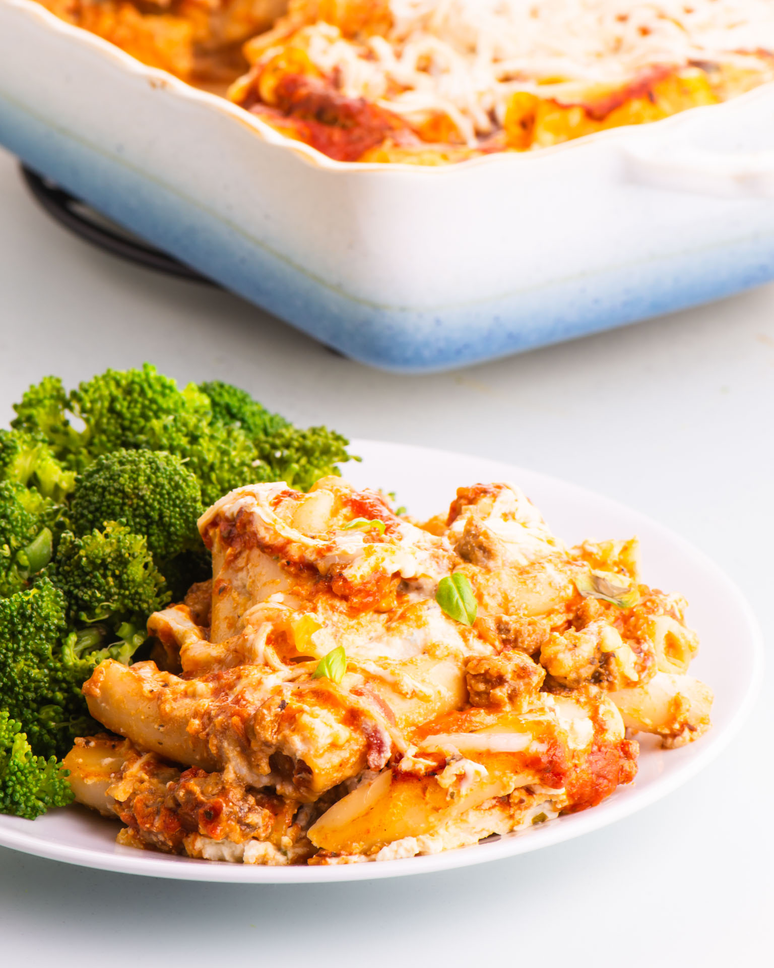 A plate full of meatless baked ziti in front of the rest of the casserole dish.