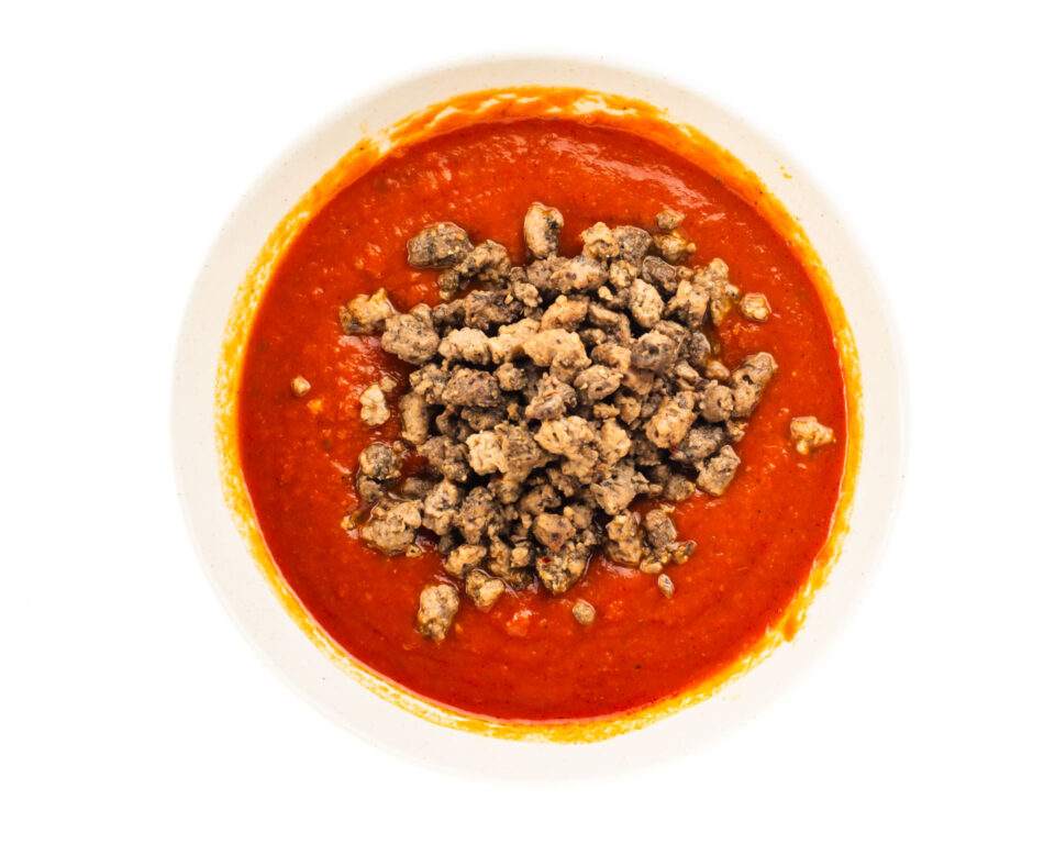 Marinara sauce in a bowl with veggie crumbles added.