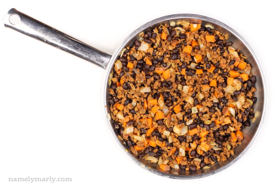 A skillet full of black beans, sweet potato cubes, and other savory ingredients.