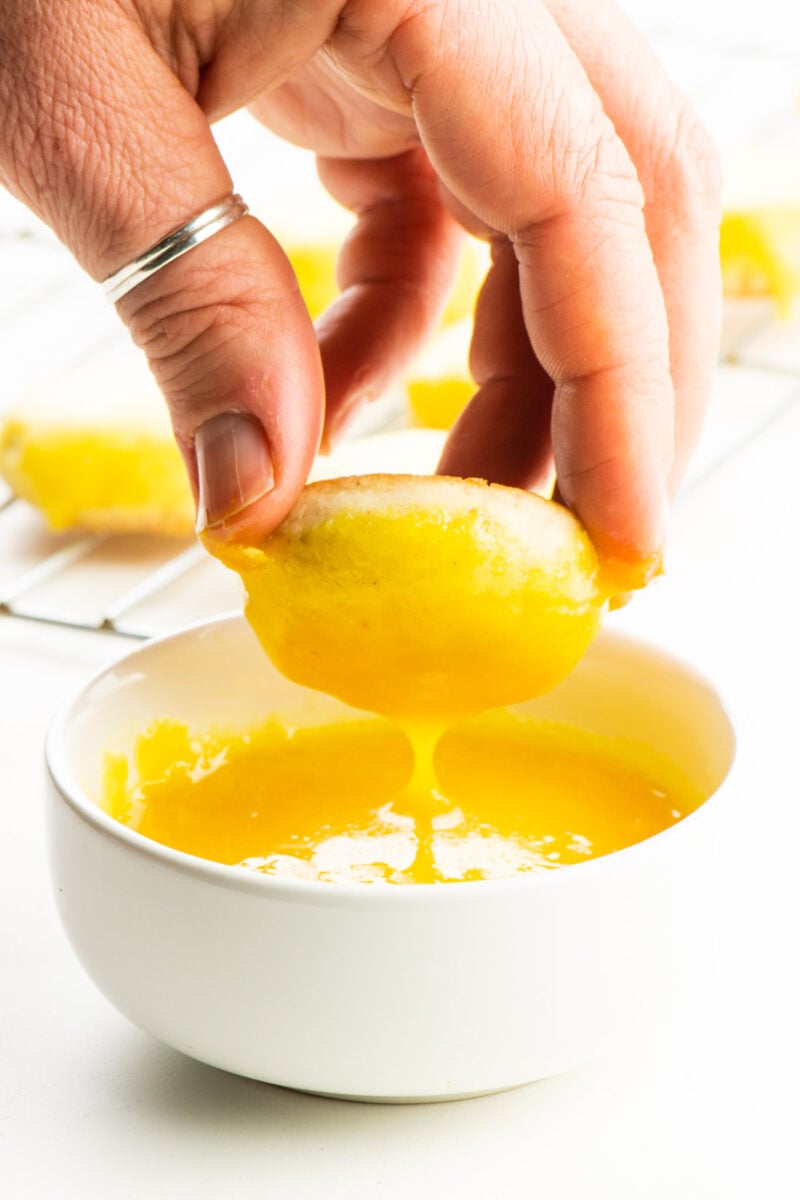 A lemon cookie is dipped in bright yellow frosting.