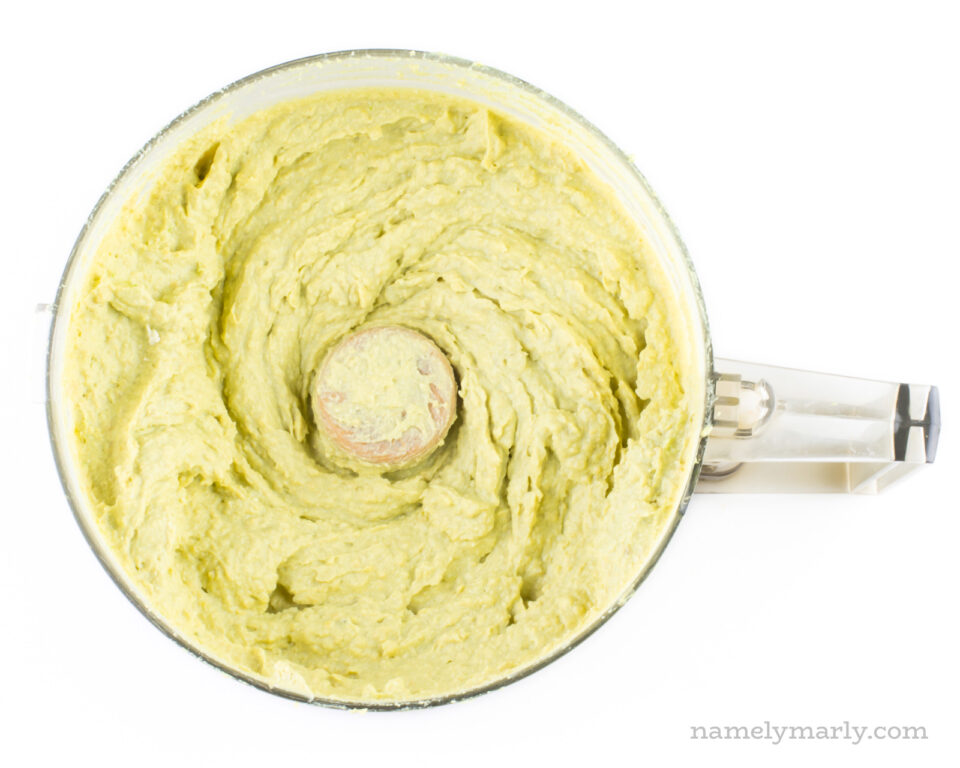 A tofu-avocado mixture in the bottom of a food processor bowl.