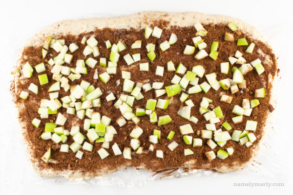 Dough is rolled out with cinnamon sugar over the top and chopped green apples.