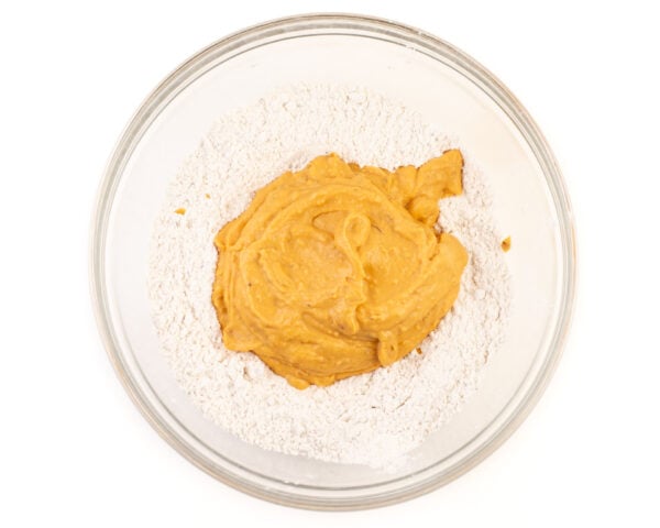 A sweet potato mixture has been added to a bowl with flour in it.