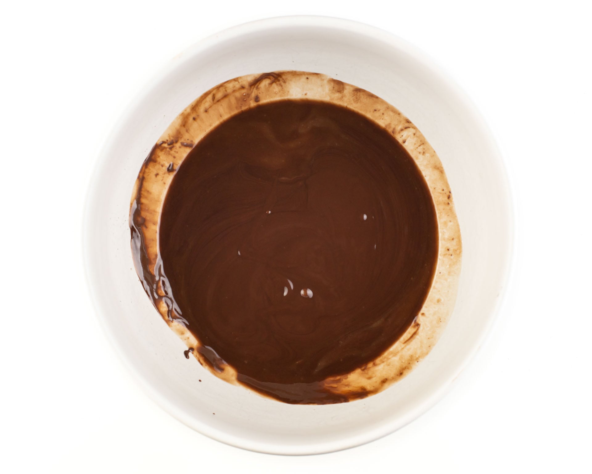 Chocolate chips, vegan butter, and coconut oil have been melted in the bottom of a glass bowl.