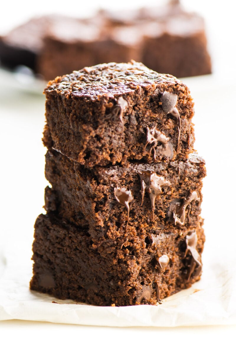A stack of vegan brownies with several more brownies behind them.