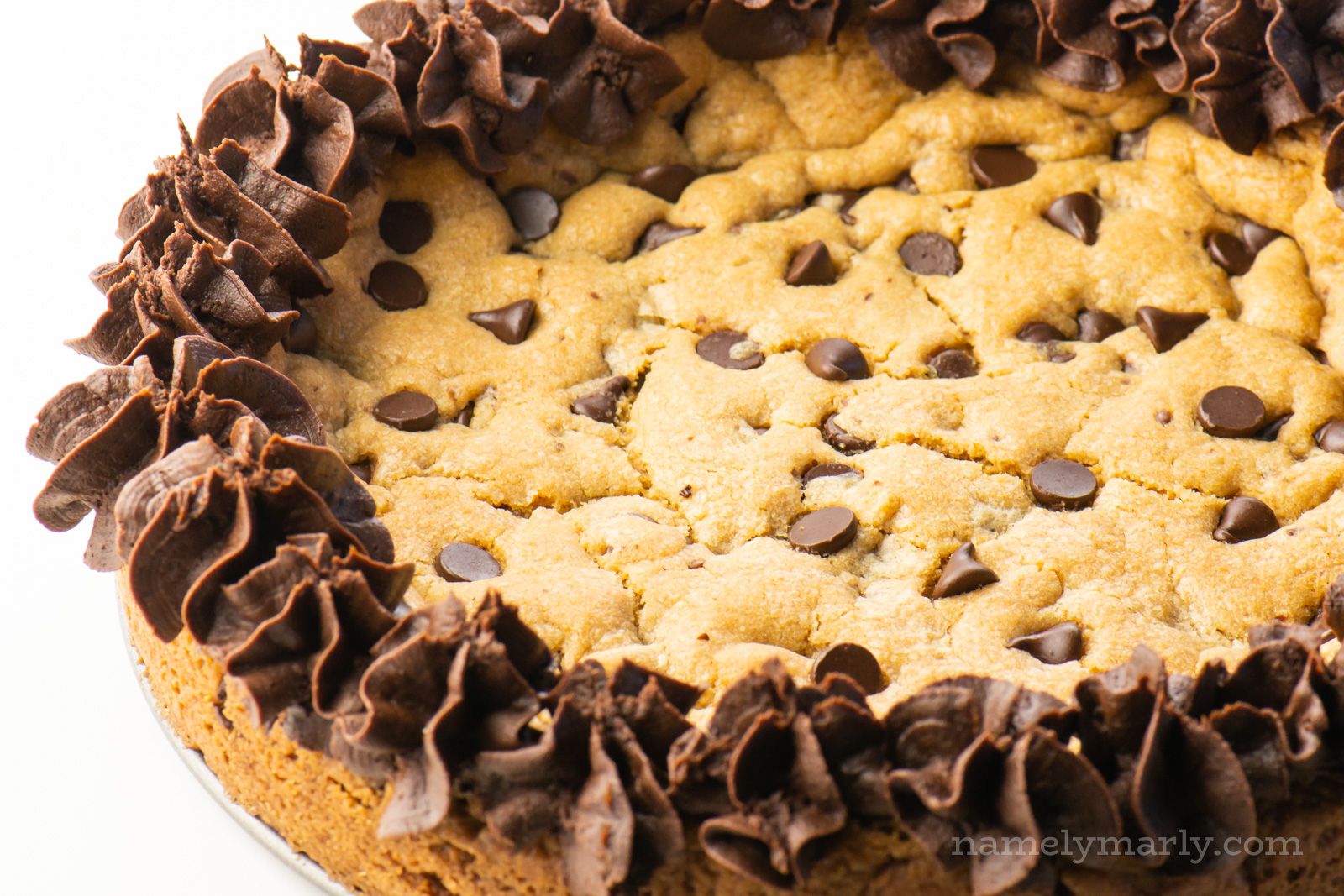A closeup of the frosting on the edge of a chocolate chip cake.