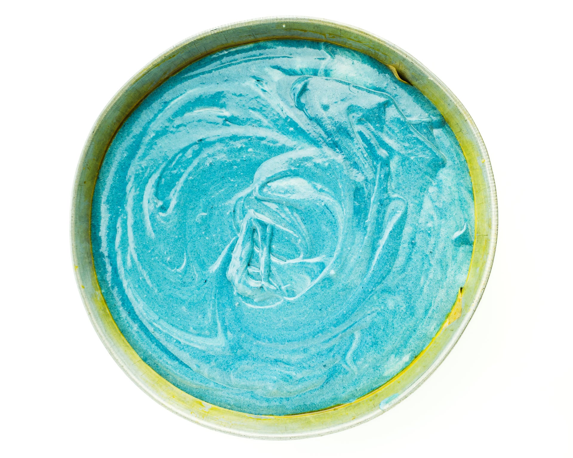 Looking down on blue cake batter in a round cake pan.