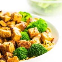 A bowl of cooked tofu with steamed broccoli.