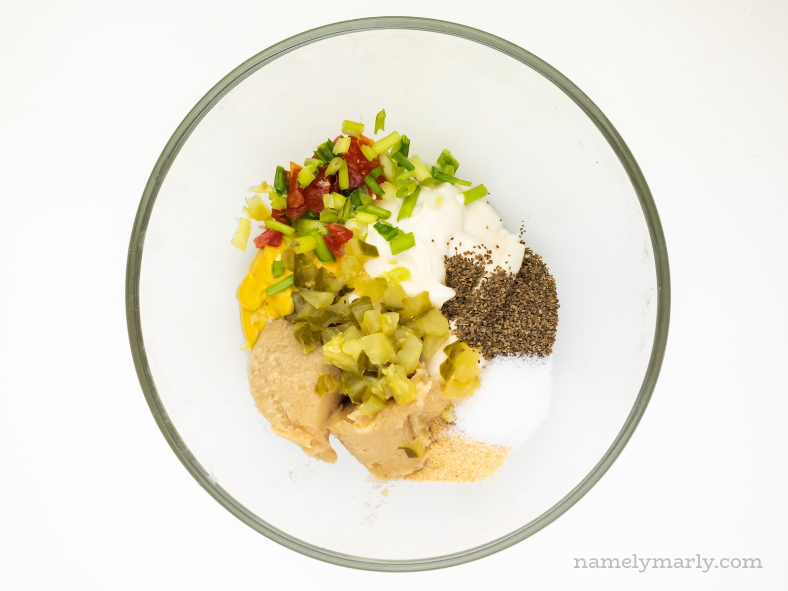 Ingredients like vegan mayo, mustard, and seasoning in a glass bowl.