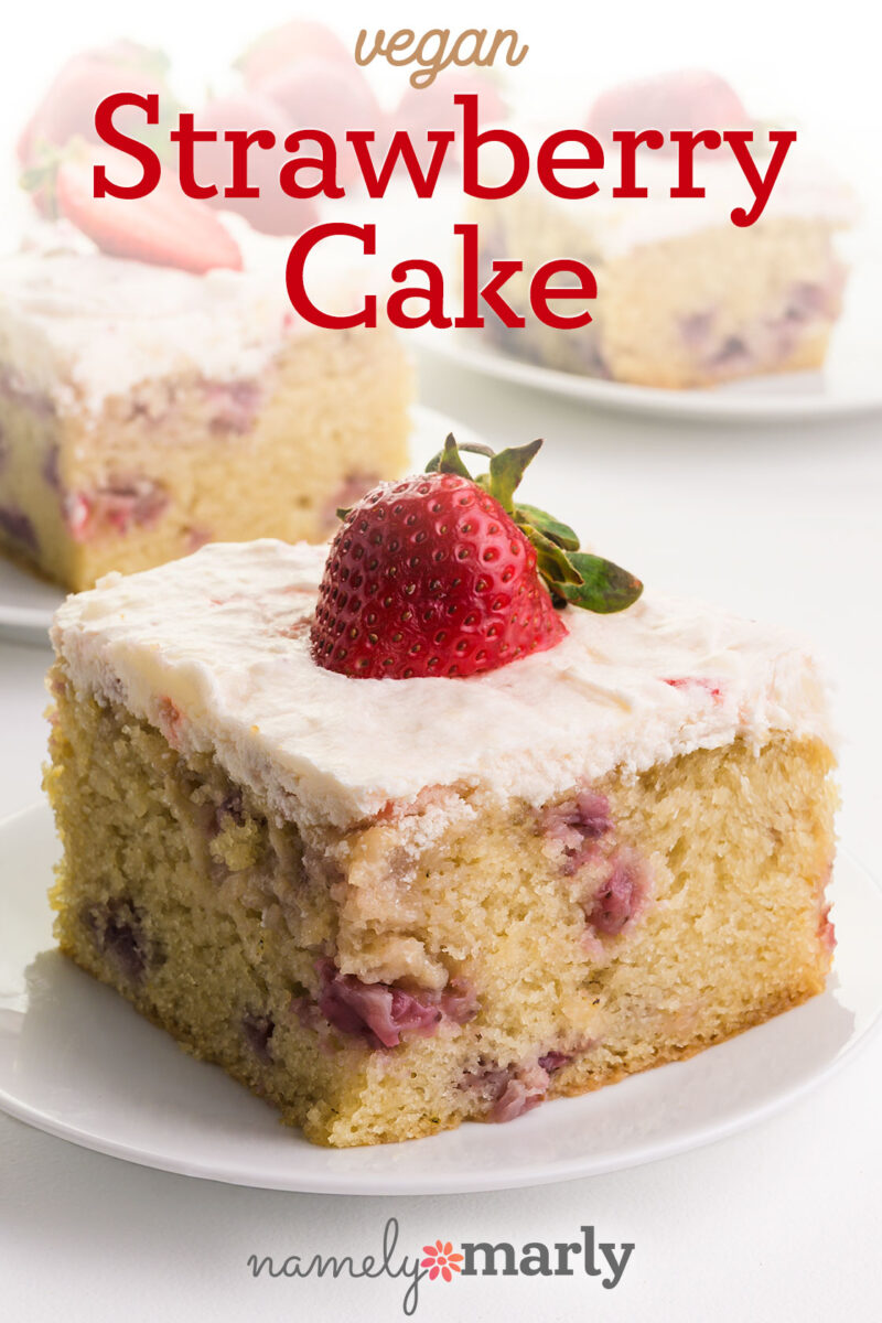 Vegan strawberry cake slice topped with a fresh strawberry and creamy frosting.
