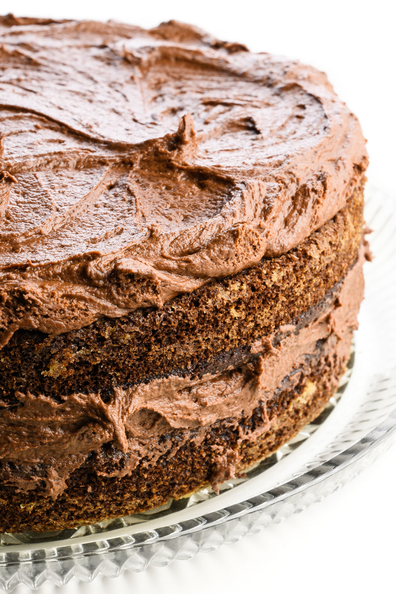 A chocolate cake has frosting on the top and between the two layers, but no frosting on the sides.