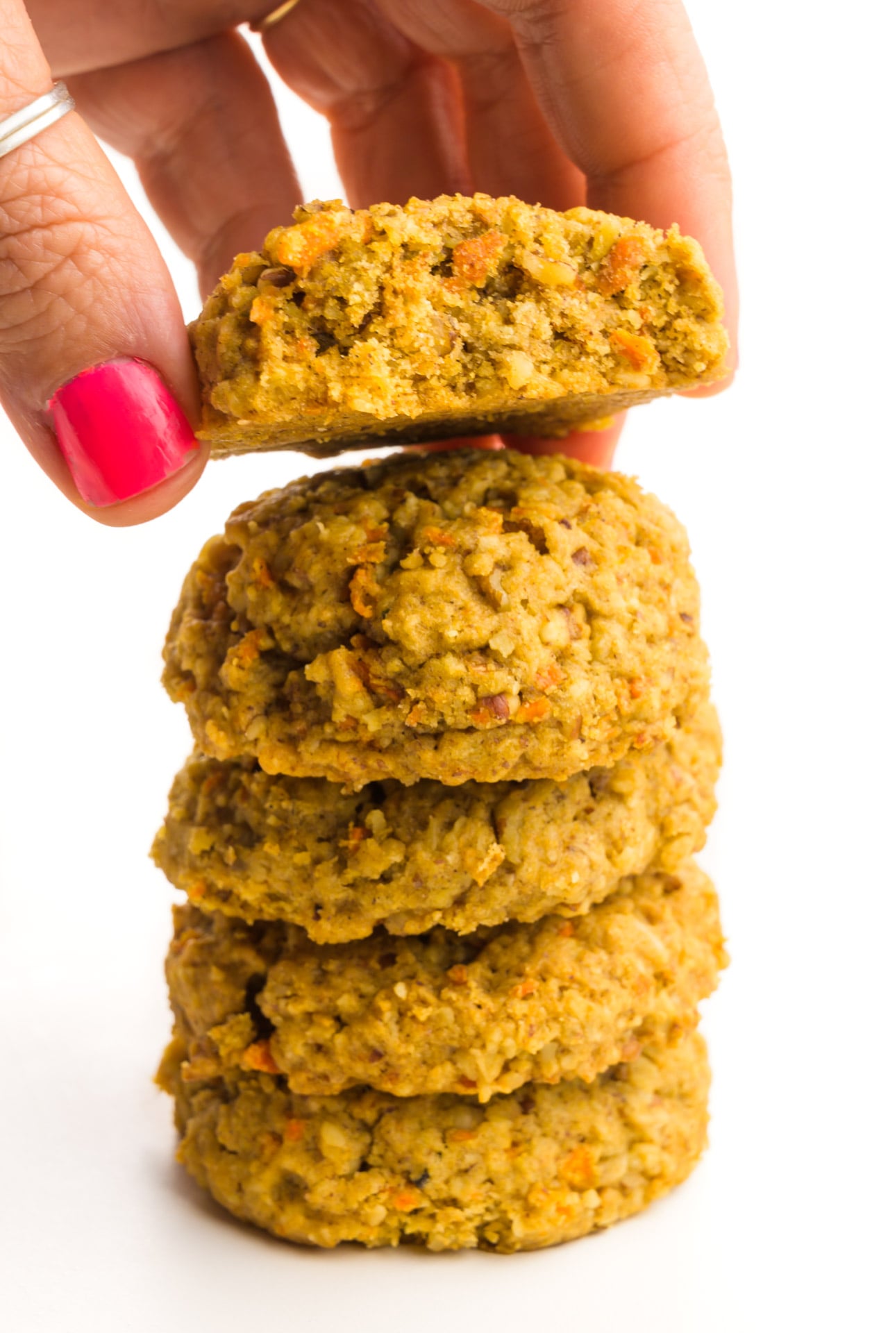 A hand grabs the top cookie from the stack of several unfrosted cookies.