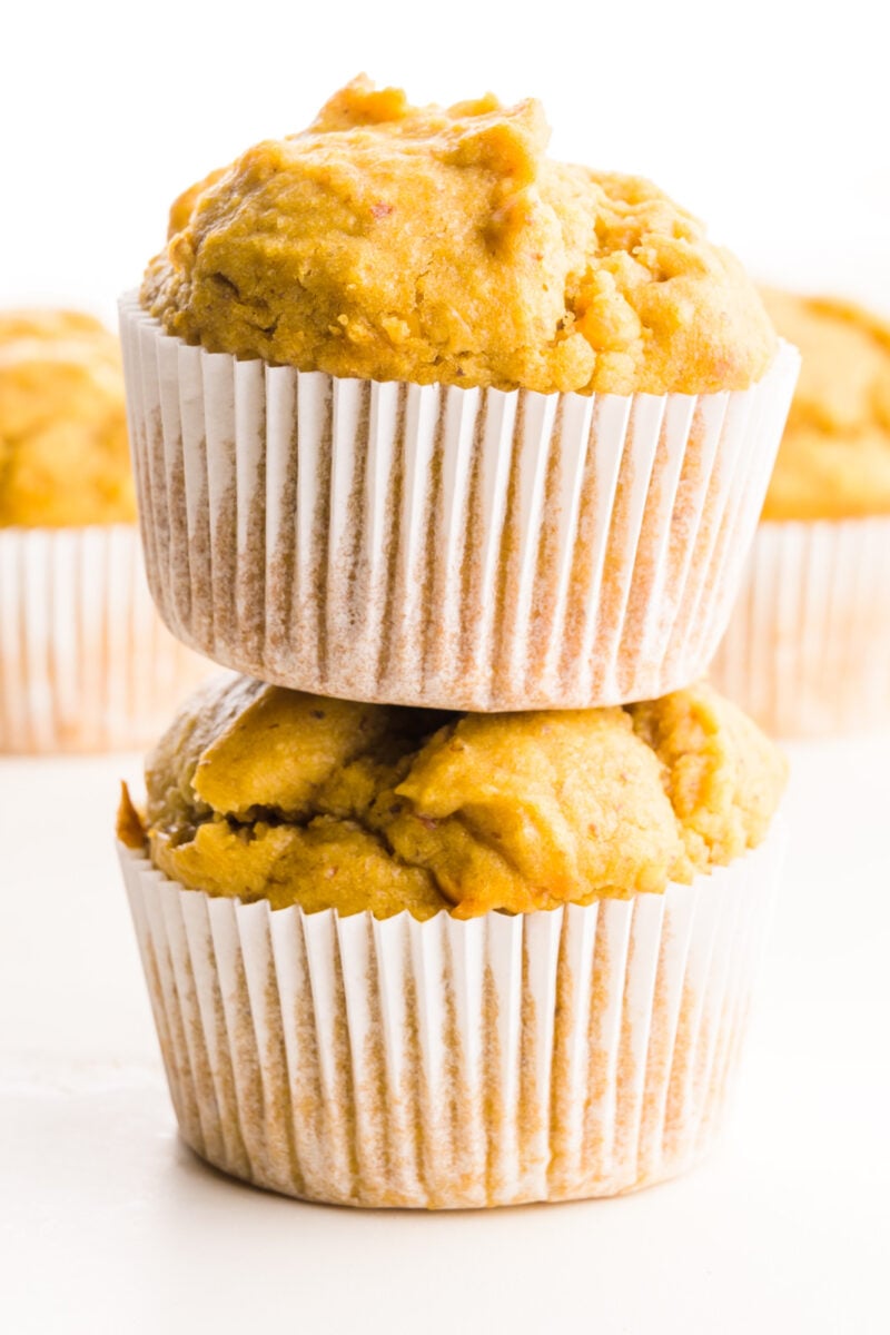 Two peanut butter muffins are stacked with more muffins behind them.