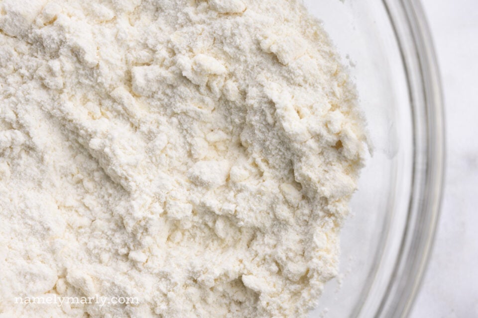 Looking down on a bowl of flour with vegan butter cut into the flour.