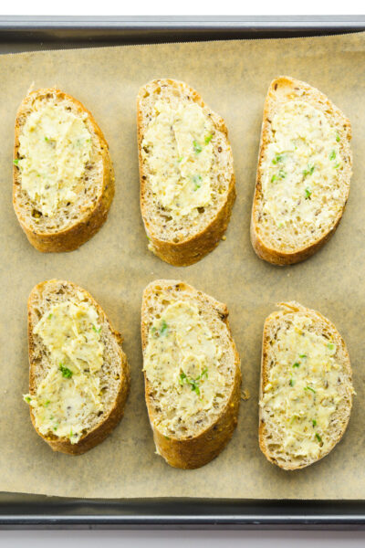 Looking down on several slices of buttered bread ready to go into the oven.
