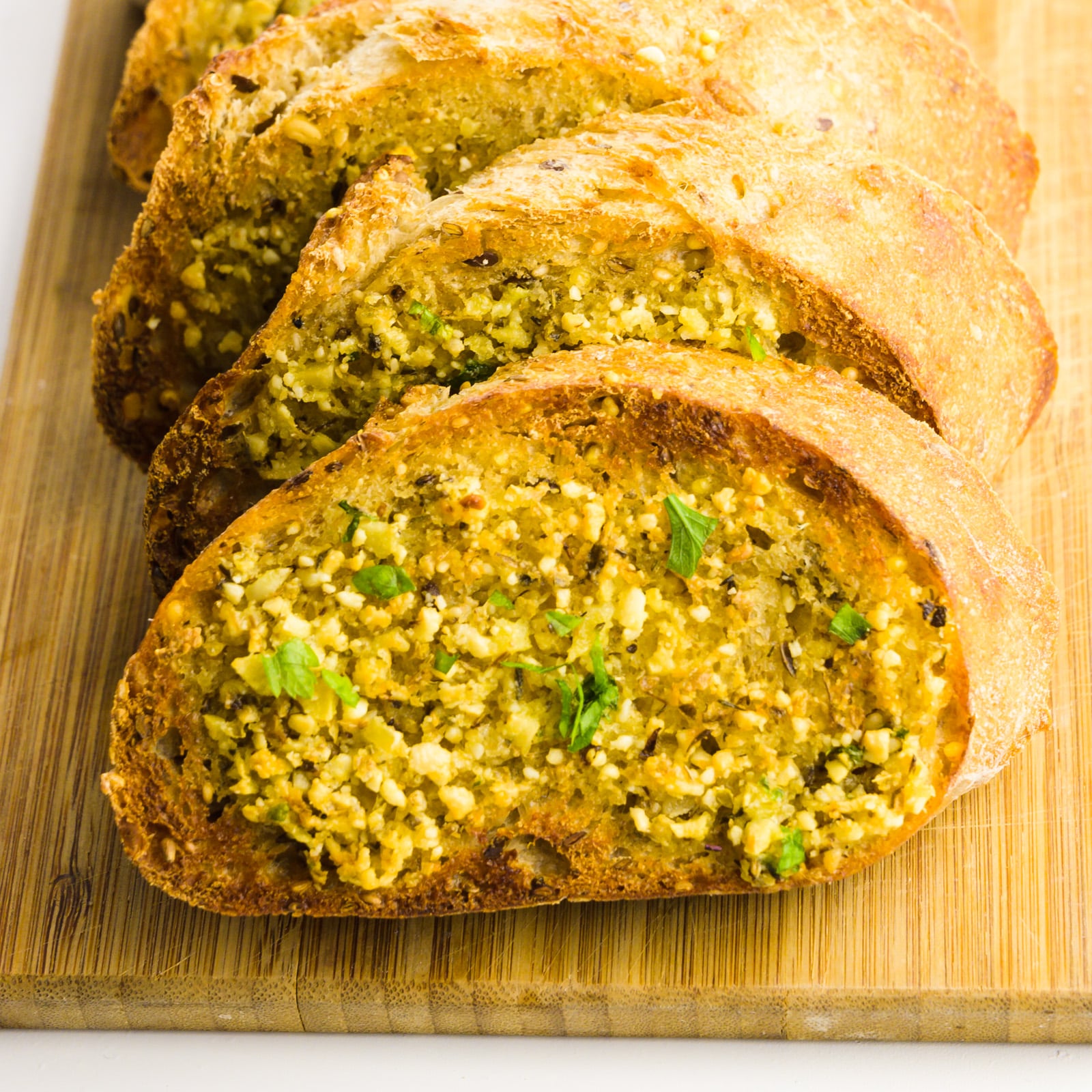 A close-up of toasted vegan garlic bread on a cutting board.