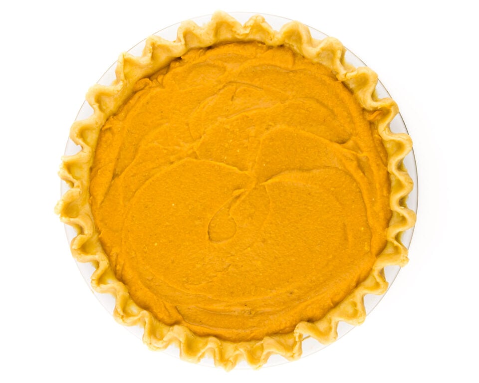 A pie shell has been recently filled with pumpkin pie filling, and is waiting to go into the oven.