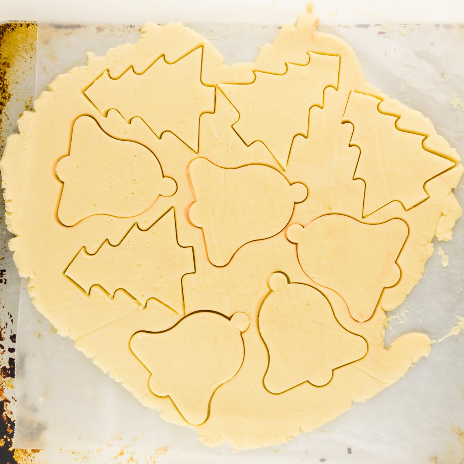 Cookie dough with cutout shapes sits on a cookie tray.