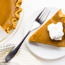A slice of pie has a fork beside it and the rest of the pie is next to it too.