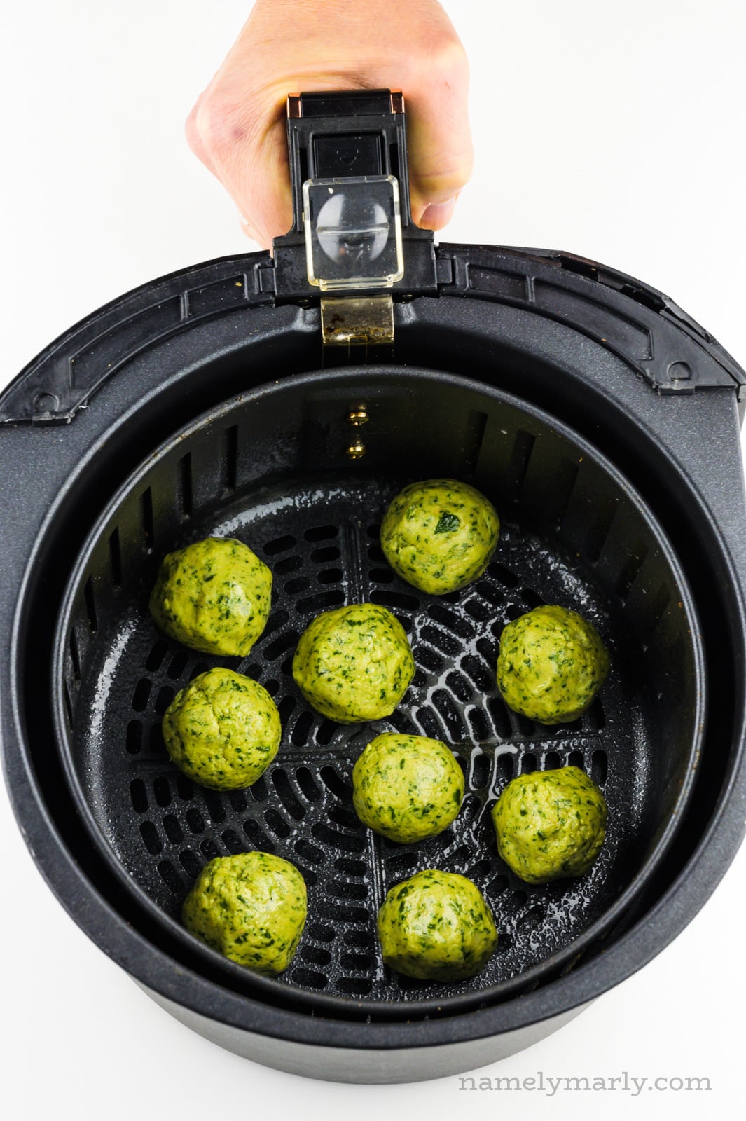 Falafel balls are in an air fryer basket.