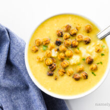 Looking down on a bowl of soup with croutons on top with a blue napkin beside it.