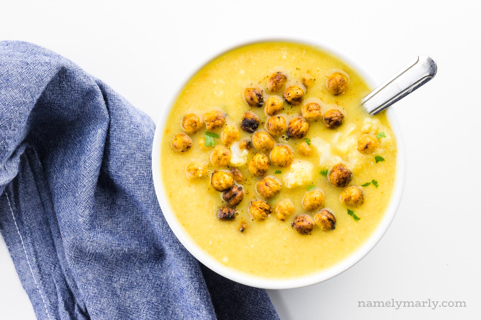 Looking down on a bowl of soup with croutons on top with a blue napkin beside it.