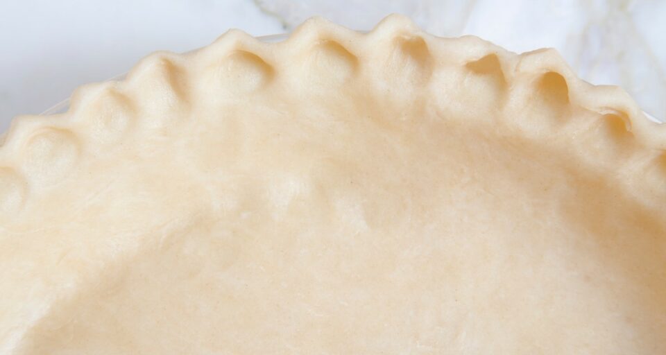 Looking down on the side of an unbaked pie crust in a pan.