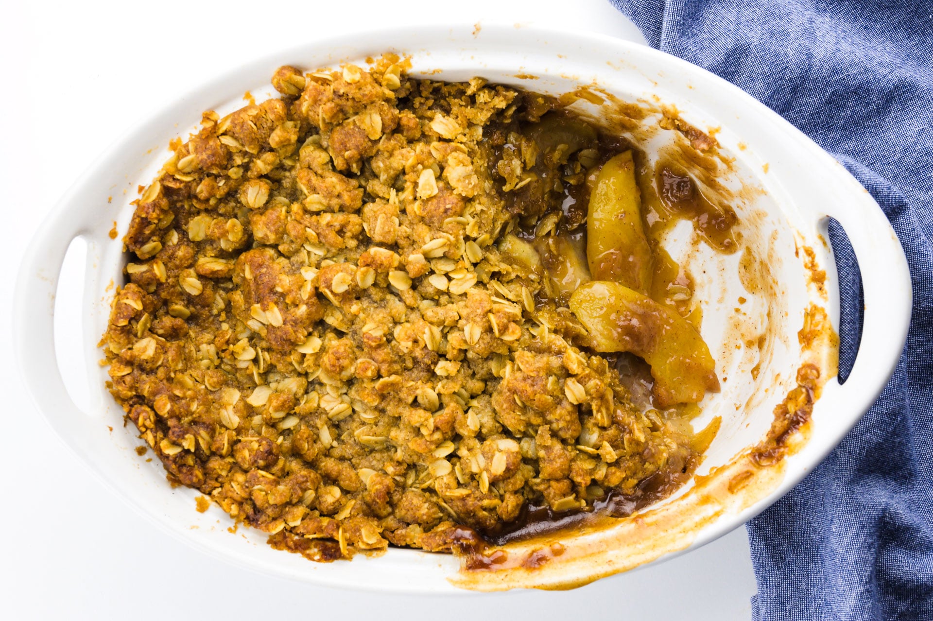 Looking down on a casserole dish full of an apple dessert, with a serving removed, showcasing sliced apples.
