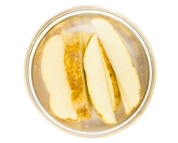Potato wedges in a bowl of water, soaking before being cooked.