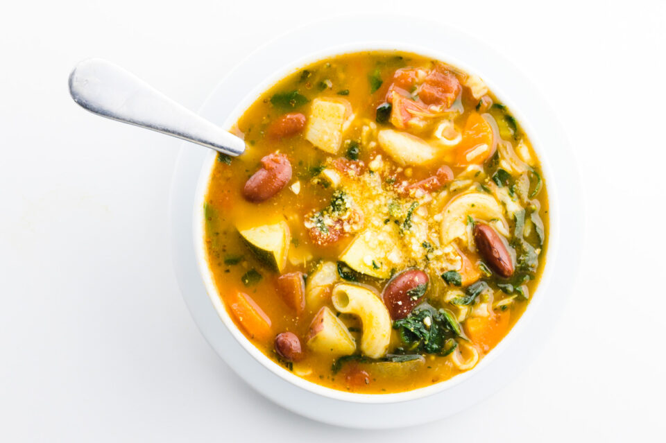 A bowl of soup has a spoon in it.