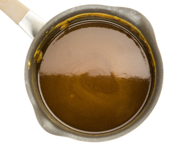A saucepan has caramel sauce in it.