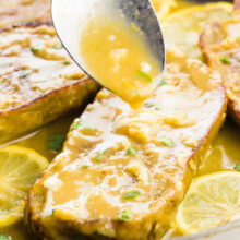 A spoon drizzles sauce over vegan chicken in a skillet.