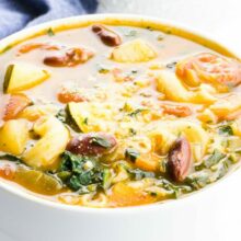 A closeup of minestrone soup with another bowl behind it.