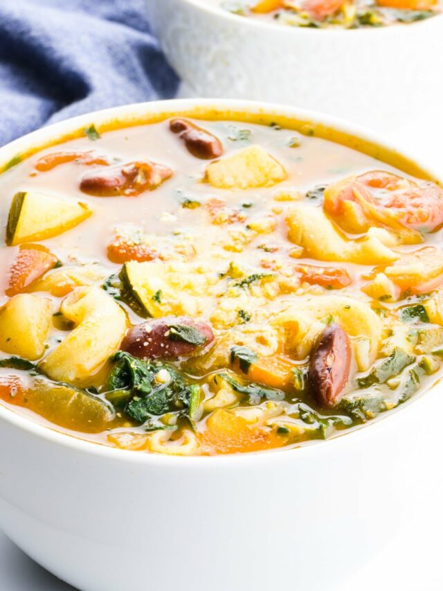 A closeup of minestrone soup with another bowl behind it.
