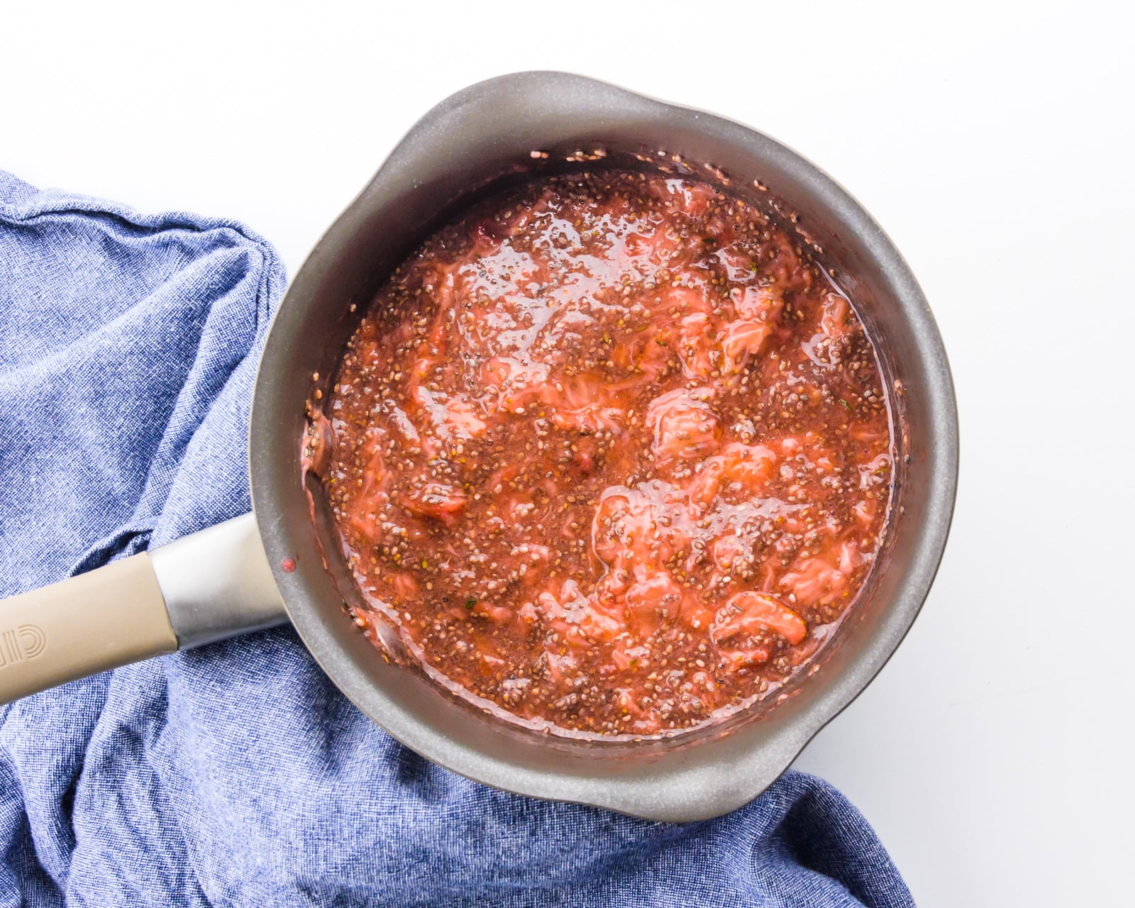 Fresh strawberries have been cooked in the bottom of a saucepan.