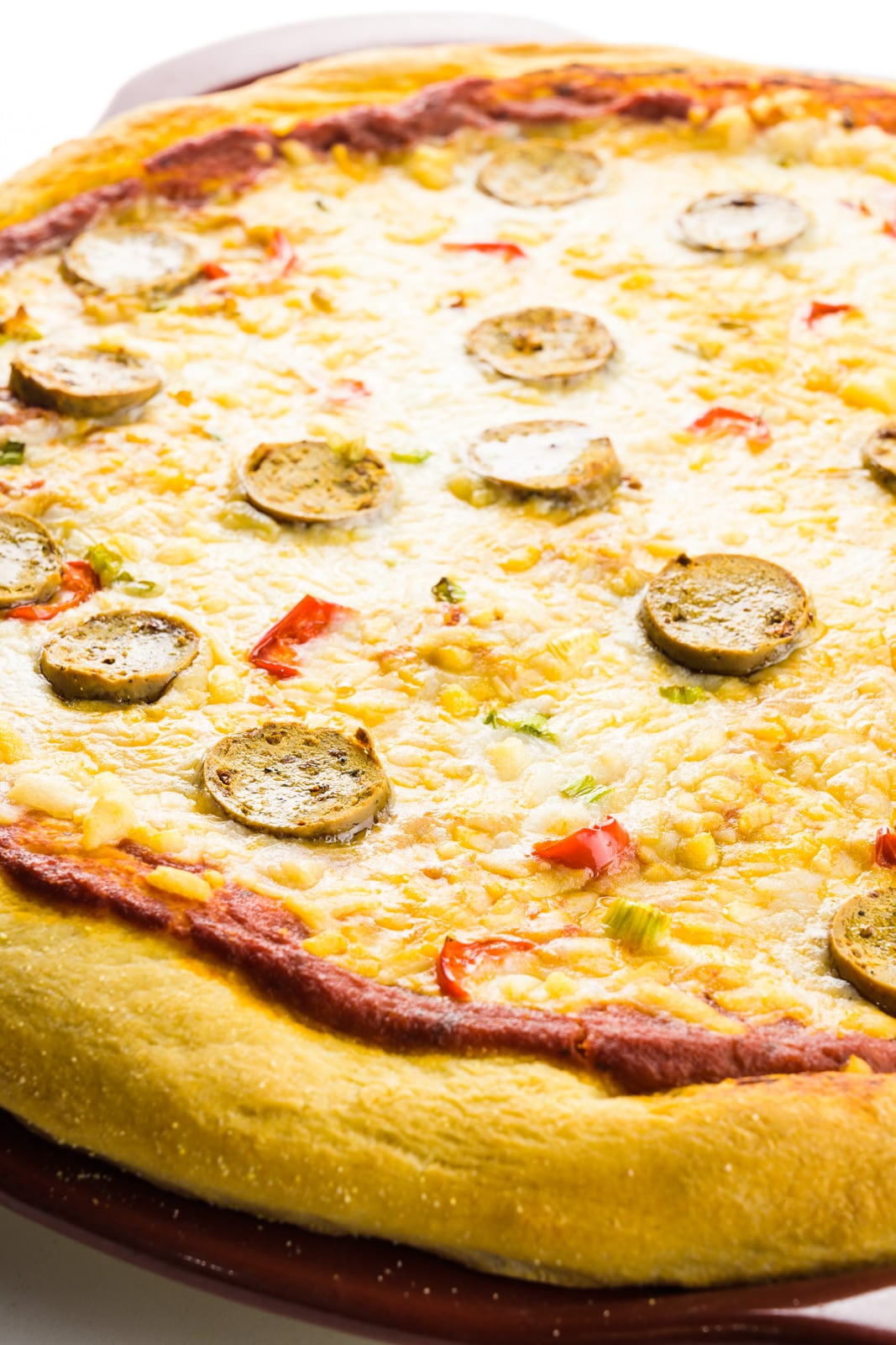 A pizza has been removed from an oven and the cheese is freshly melted and golden in places.