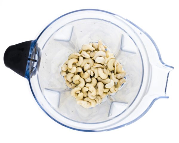 Cashews are in the bottom of a blender jar, waiting to be processed.
