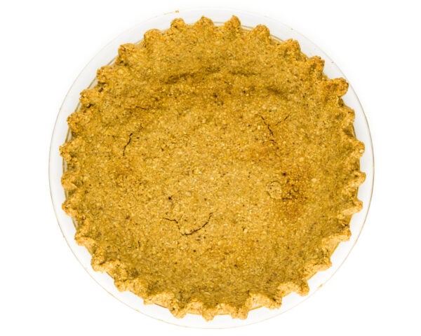 An oatmeal pie crust fresh from the oven sits on a white table.