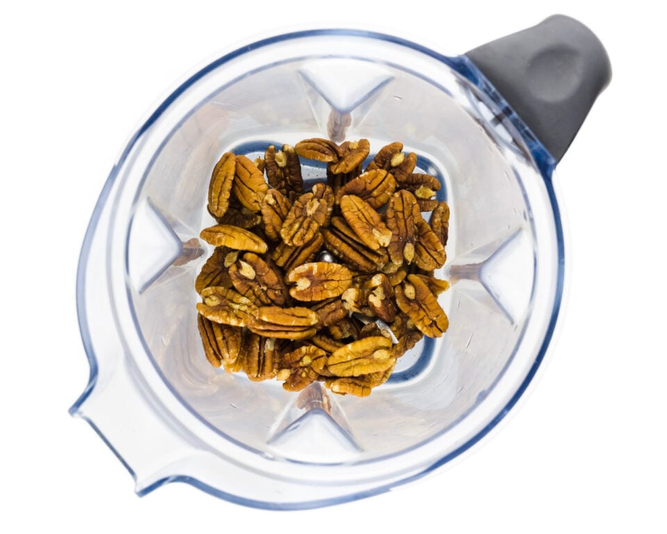 Pecans are in the bottom of a blender.