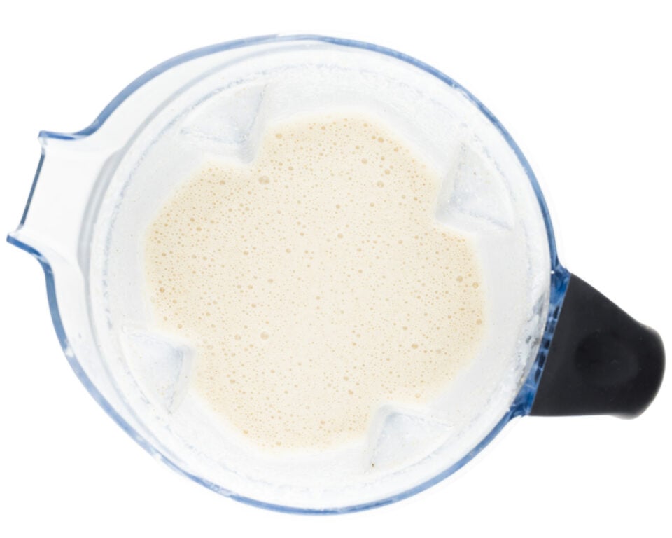 Nut milk is in the bottom of a blender.