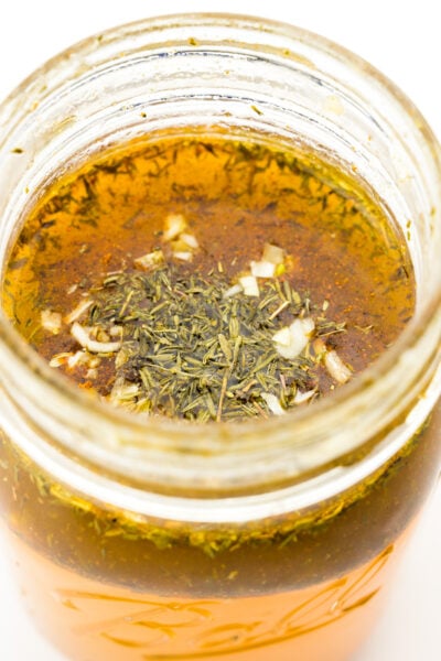 Looking into a mason jar full of ingredients to make Italian vinaigrette.