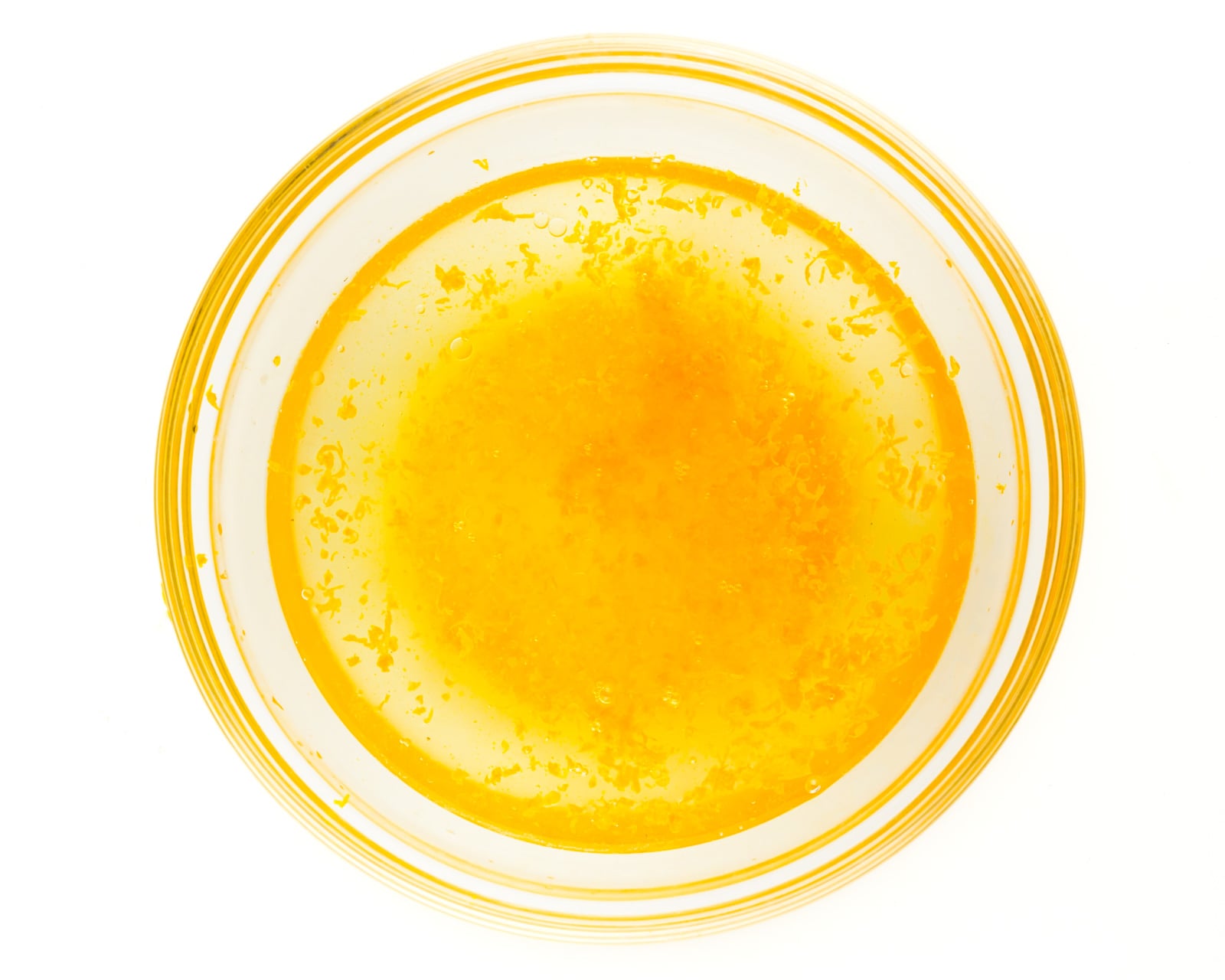 Looking down on a bowl full of water, oil, and orange zest.