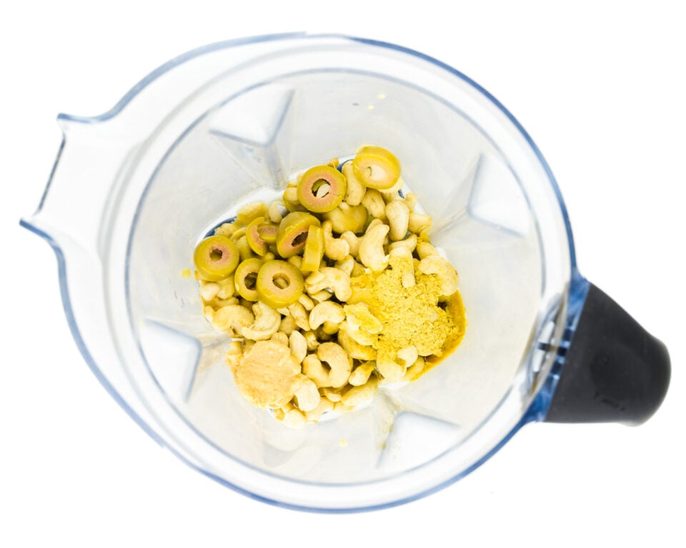 Looking down in a blender jar with cashews and other ingredients.