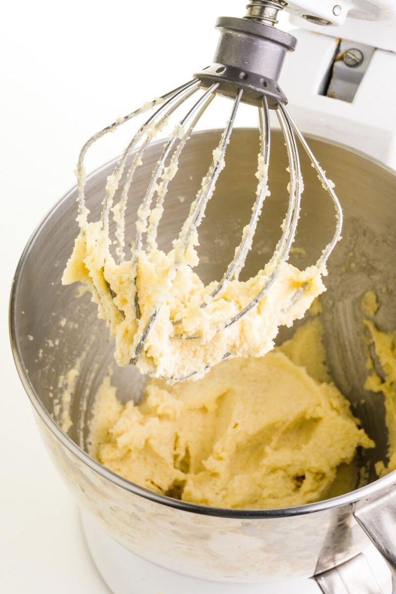 Butter and sugar have been whipped together in a mixing bowl of a stand mixer.