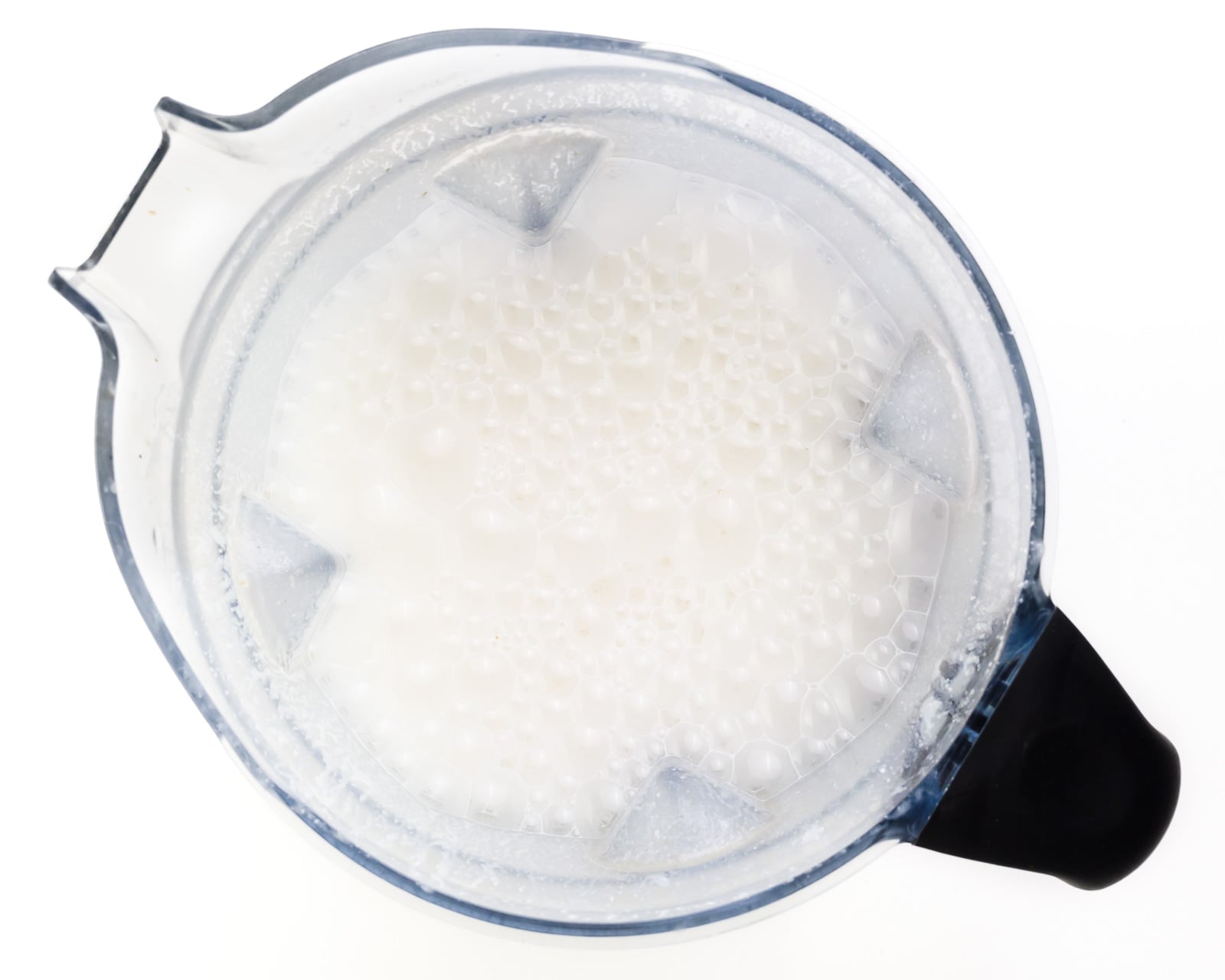 Cashew milk is nice and frothy in the bottom of a blender jar.