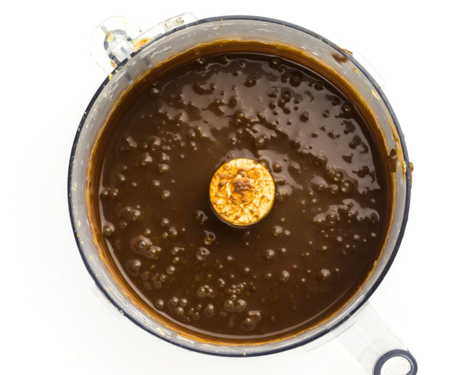 Chocolate sauce is in the bottom of a food processor bowl.